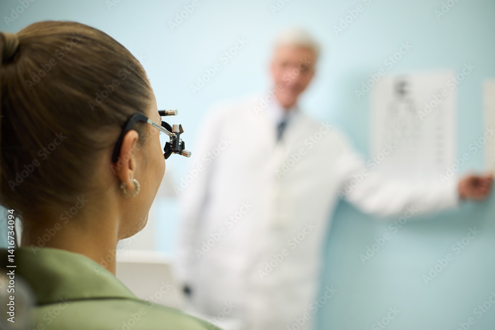 Obraz premium Patient attended examination with an ophthalmologist who is blurred in background. Professional setting with medical focus in an eye clinic, ensuring patient's visual health