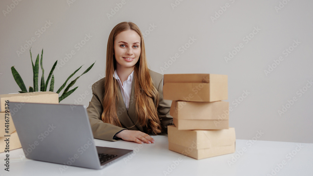Woman in business attire sitting at desk with laptop and stacked boxes during daytime Woman in business attire sitting at desk with laptop and stacked boxes during daytime
