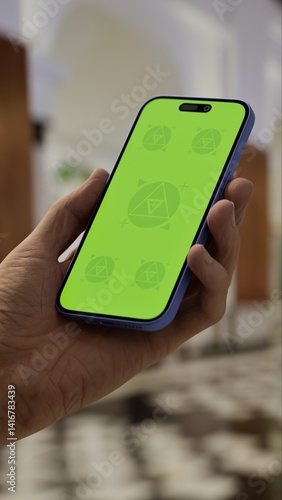 GREEN SCREEN CHROMA KEY Person holding a smartphone in a luxurious lobby with elegant architecture, marble flooring, and blurred background activity