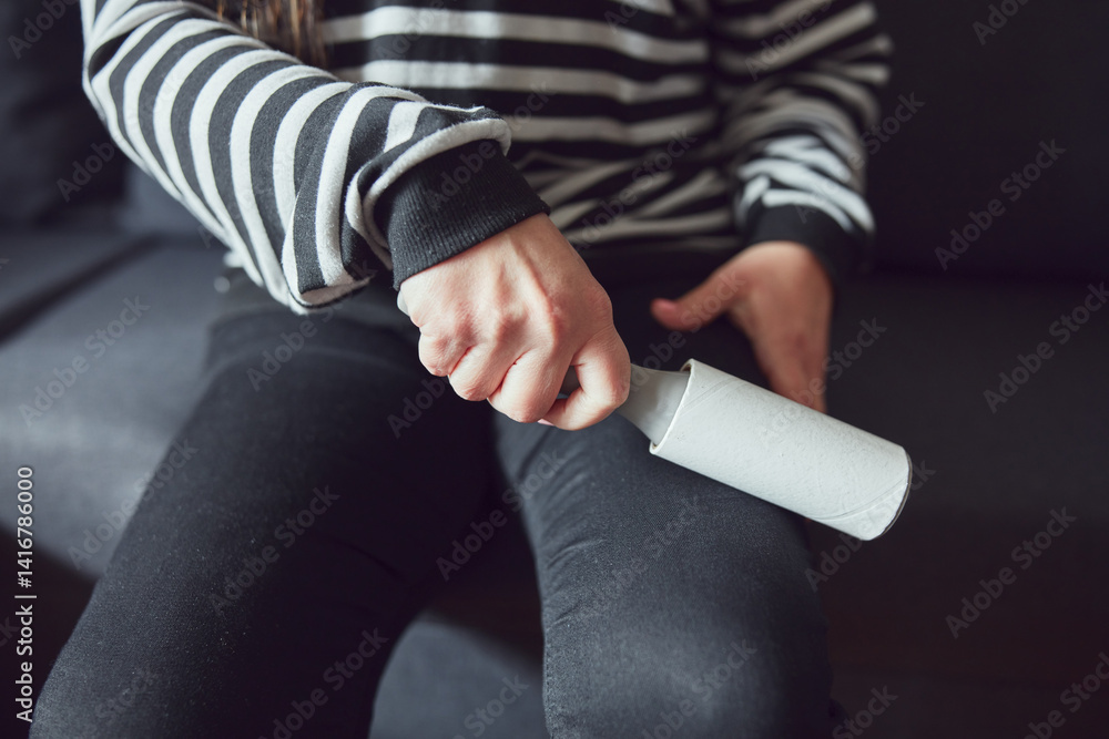 Woman cleaning clothes with a sticky lint roller.