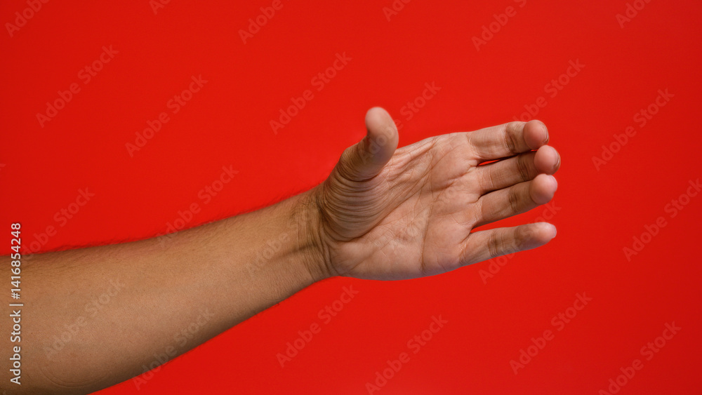 Man's hand extended in a handshake gesture against a vivid red background, highlighting the neutral skin tone and smooth texture. Man's hand extended in a handshake gesture against a vivid red background, highlighting the neutral skin tone and smooth texture.