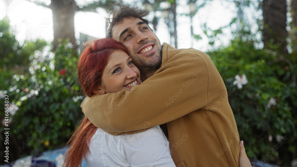 Fototapeta premium Man and woman embrace in a city park, showcasing a joyful and loving relationship against a backdrop of greenery, embodying happiness and togetherness outdoors.