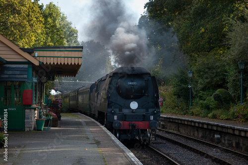 a battle of Britain class pacific locomotive traveling through a southern station in the uk