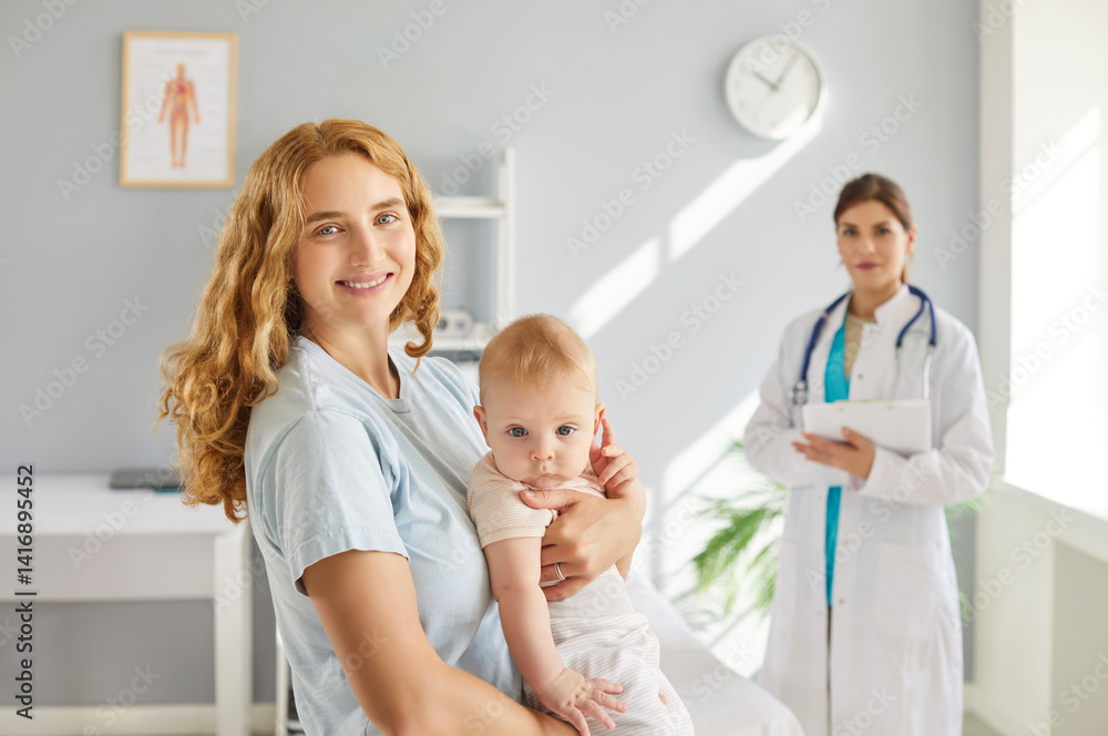 Portrait of young cheerful mother with toddler baby visiting female pediatrician in medical office. Happy mom holding newborn kid on her hands during medical checkup in clinic. Childcare concept.