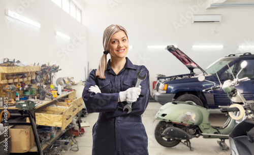 Female auto mechanic worker in a uniform holding a wrench
