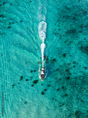 Obraz na płótnie A fast boat glides through shallow crystal-clear waters, leaving a white trail on the turquoise sea in Thailand. w salonie