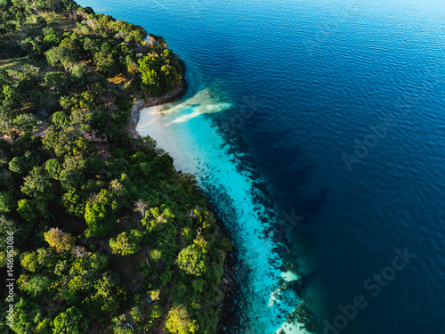 Obraz na płótnie Tropical forest meets a white sandy beach with turquoise water along a curved island coastline, seen from above in Thailand. w salonie