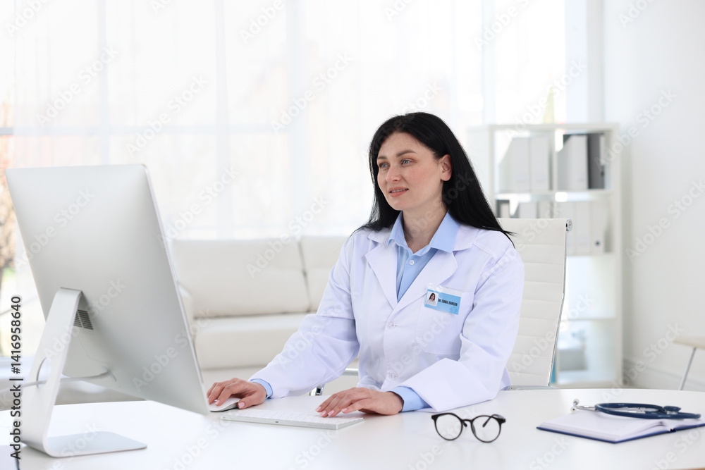 Professional doctor working on computer at white desk in hospital Professional doctor working on computer at white desk in hospital