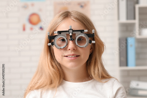 Vision care and eye health, young girl wearing trial frame glasses during an ...