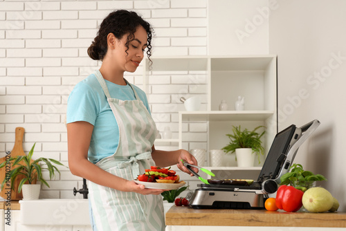 Healthy cooking and home meal preparation, woman using electric grill to prep...