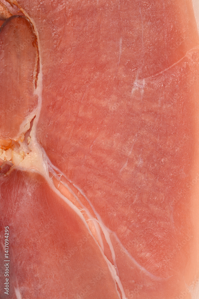 A close-up shot reveals the texture and marbling of a slice of dry-cured ham with visible fat striations