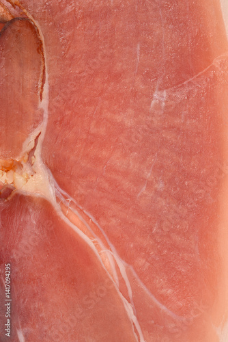 Obraz na płótnie A close-up shot reveals the texture and marbling of a slice of dry-cured ham with visible fat striations w salonie