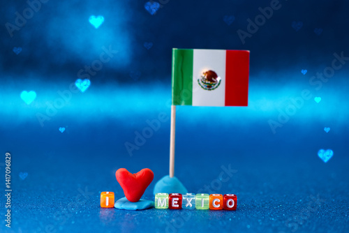 Obraz na płótnie Colorful display featuring a Mexican flag, a heart symbol, and letter blocks expressing love for Mexico against a vibrant blue background w salonie