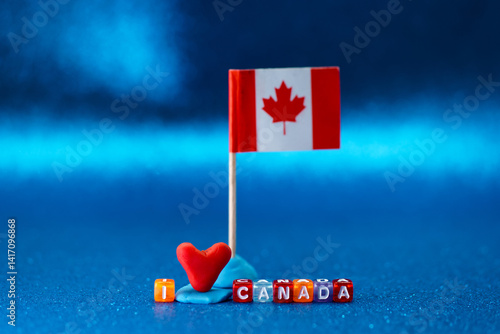 Creative display of a Canadian flag with love heart and letter blocks on blue background for celebrating Canadian pride and heritage