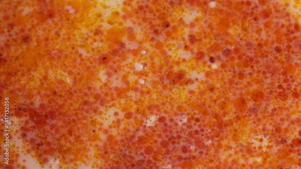 Oily red curry bubbles, close-up of white curry laksa soup surface with chili oil Oily red curry bubbles, close-up of white curry laksa soup surface with chili oil