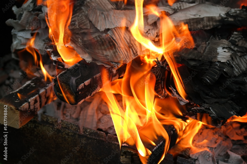Fototapeta premium burning wood and paper. firewood is burning. tongues of flame. orange flame. bonfire. wood-fired cooking. firewood is burning for cooking barbecue