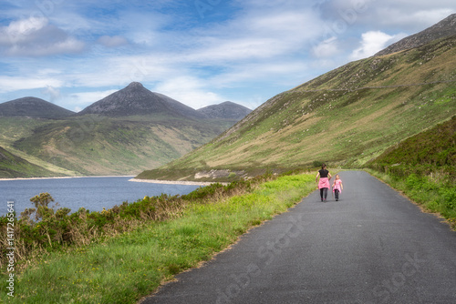 Obraz na płótnie Mother and her joyful child leisurely stroll along Silent Valley Reservoir path that is beautifully surrounded by majestic Mourne Mountains and lush, vibrant greenery all around them, Northern Ireland w salonie