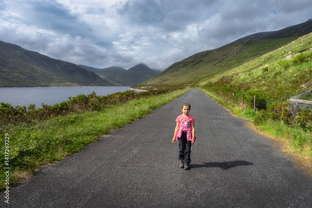 A child enjoys serene and peaceful walk along a beautiful and scenic path by a picturesque Silent Valley Reservoir, which is surrounded by lush greenery and majestic Mourne Mountains, Northern Ireland