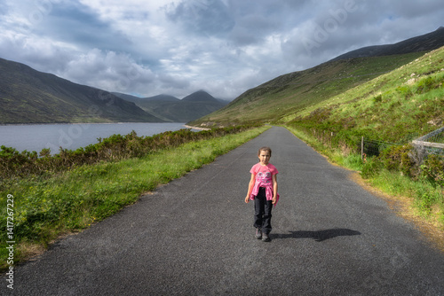 Obraz na płótnie A child enjoys serene and peaceful walk along a beautiful and scenic path by a picturesque Silent Valley Reservoir, which is surrounded by lush greenery and majestic Mourne Mountains, Northern Ireland w salonie
