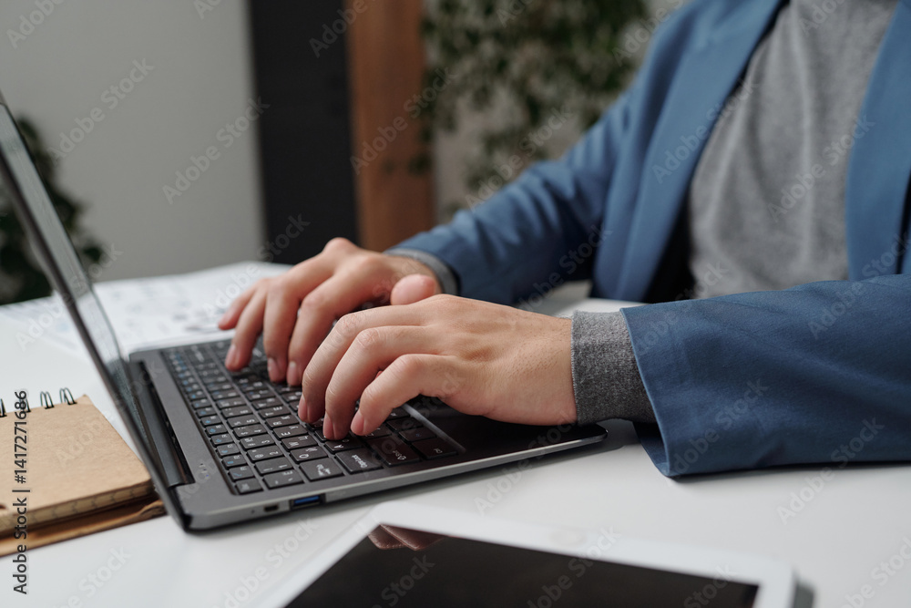 Side view closeup of male hands typing at laptop keyboard with unrecognizable businessman using computer at workplace. copy space Side view closeup of male hands typing at laptop keyboard with unrecognizable businessman using computer at workplace. copy space