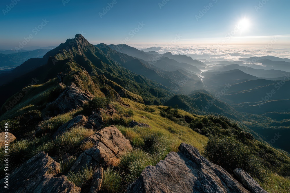 Fototapeta premium Panoramic mountain view from summit with sunlit green ridges and dramatic rocky shadows.