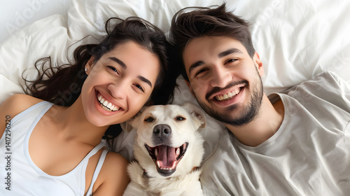 Professional image of happy young couple and dog relaxing on white bed