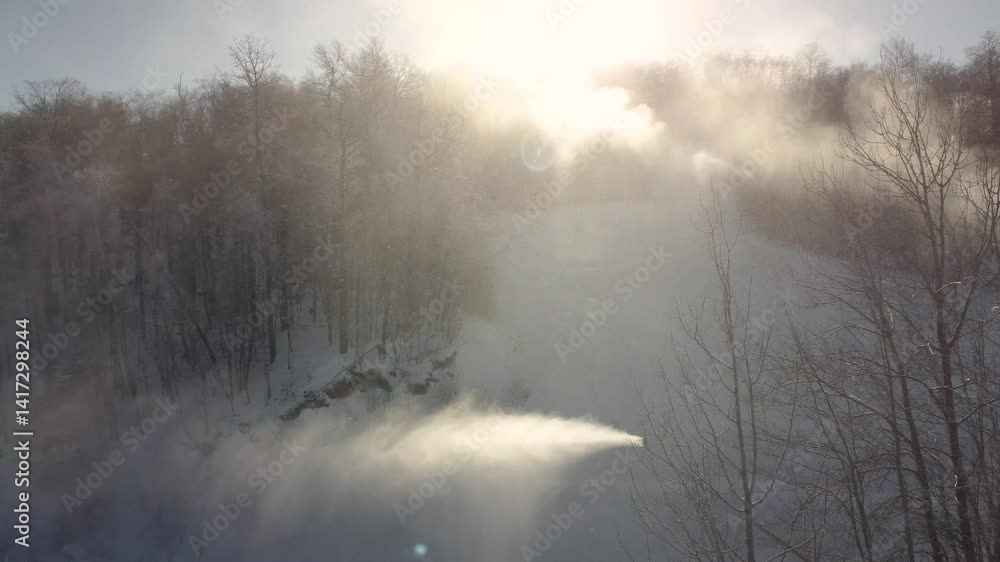 Machines producing snow on ski track on sunny day, aerial view Machines producing snow on ski track on sunny day, aerial view