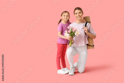 Cute little girl with bouquet of flowers greeting her sporty mother on pink background. Mother Day celebration