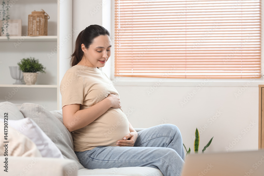 Young pregnant woman sitting on sofa at home Young pregnant woman sitting on sofa at home