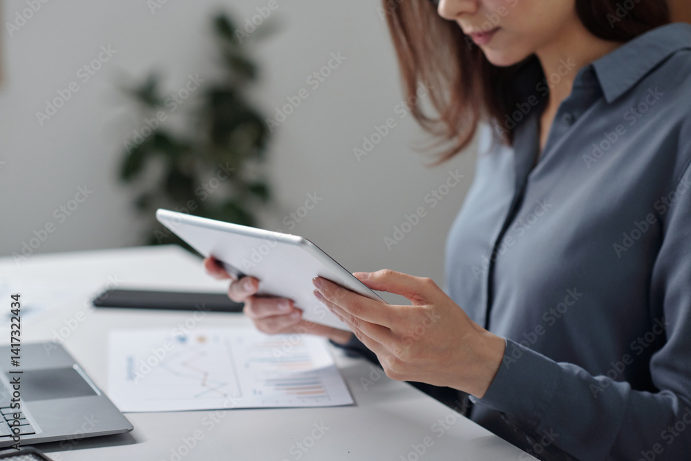 Side view cropped shot of young businesswoman using digital tablet for work in minimal office setting copy space