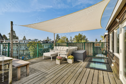 Obraz na plátně A stylish rooftop patio features comfortable seating, planters, and a protective shade sail, offering a relaxing outdoor space with a view