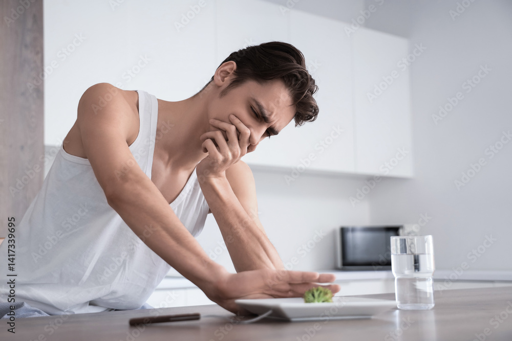 Young man with anorexia refusing from food in kitchen Young man with anorexia refusing from food in kitchen