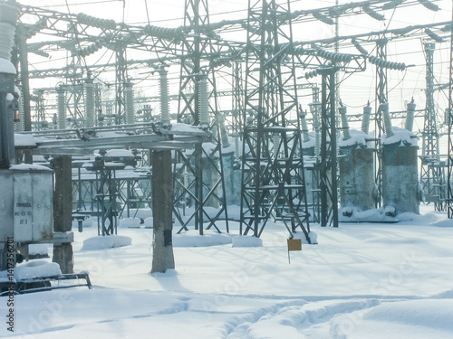 Snowy industrial landscape of electrical substation in winter. Power plant electricity infrastructure. Snowy outdoor scene for energy, engineering and industrial concept.