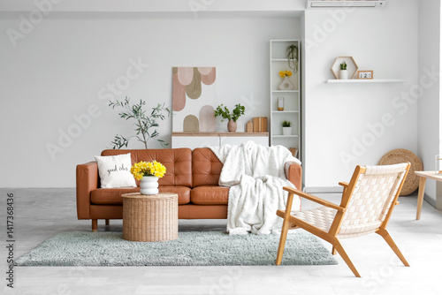 Obraz na płótnie Interior of light living room with brown sofa, armchair and daffodils in vases w salonie
