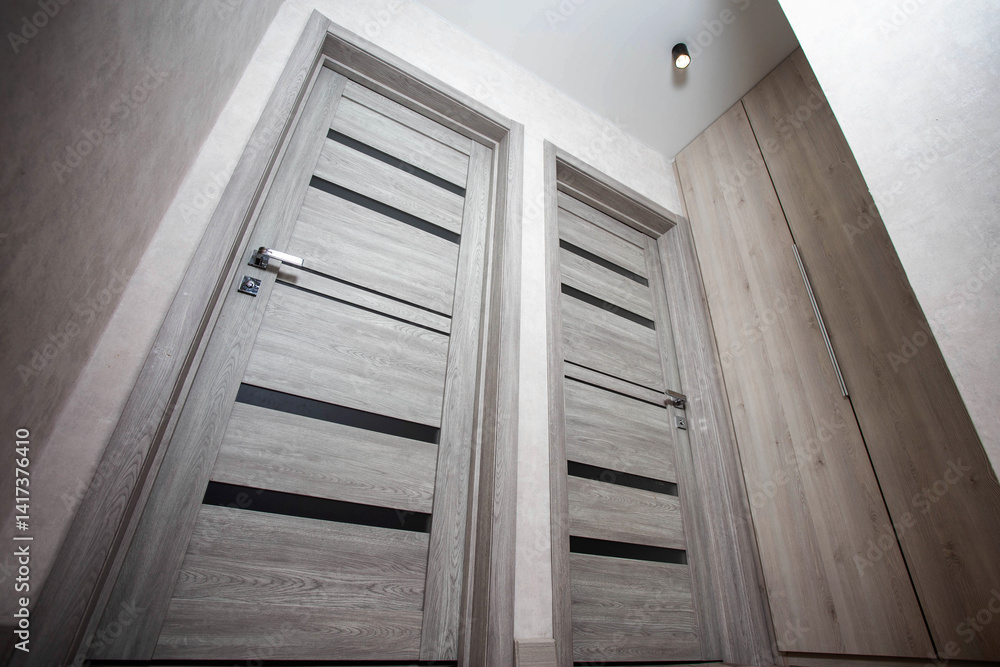 Obraz premium Two modern gray doors with glass inserts for entering and exiting the bedrooms in the apartment, modern interior