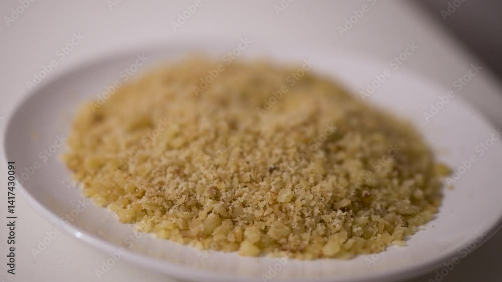 Reviro, a rustic fried flour crumb dish typical of rural Argentina, is served dry on a white plate with its grainy texture highlighted in a smooth slow motion close-up angle. Reviro, a rustic fried flour crumb dish typical of rural Argentina, is served dry on a white plate with its grainy texture highlighted in a smooth slow motion close-up angle.