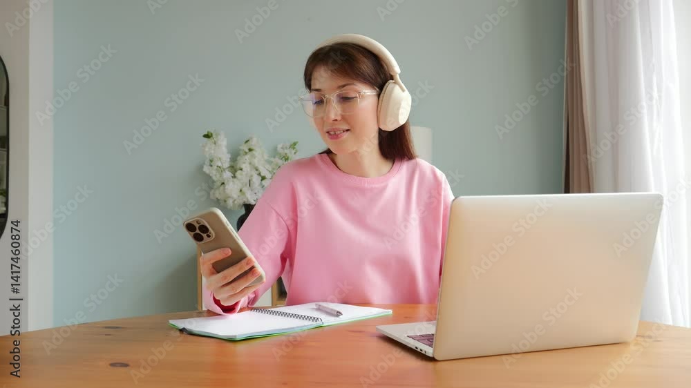 Cheerful Student Engages in Online Study Session With Laptop and Smartphone in Cozy Home Office Cheerful Student Engages in Online Study Session With Laptop and Smartphone in Cozy Home Office