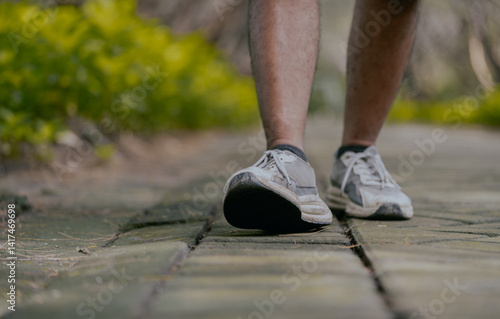 Close up of fitness man athlete walking on the park. Person running working out living an active lifestyle training cardio in summer. Lower body banner crop.