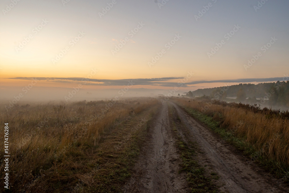 Picturesque view of landscape against sky in foggy weather. Warm autumn morning. Picturesque view of road in field against sky during sunrise Picturesque view of landscape against sky in foggy weather. Warm autumn morning. Picturesque view of road in field against sky during sunrise