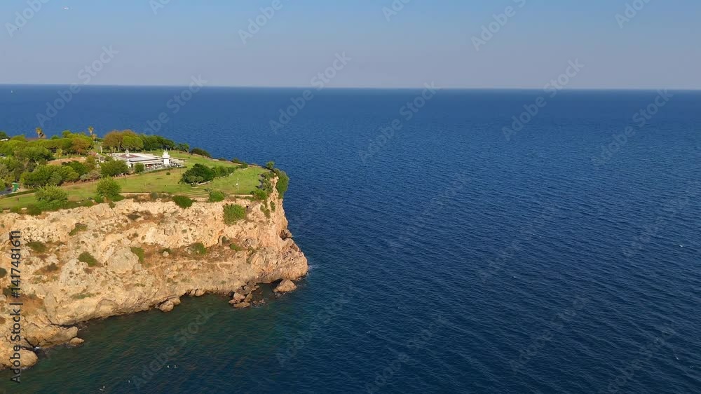 Drone tilts downward to reveal swimmers in clear, vibrant turquoise-blue water near a rugged shoreline with rocks and coastal textures. Drone tilts downward to reveal swimmers in clear, vibrant turquoise-blue water near a rugged shoreline with rocks and coastal textures.