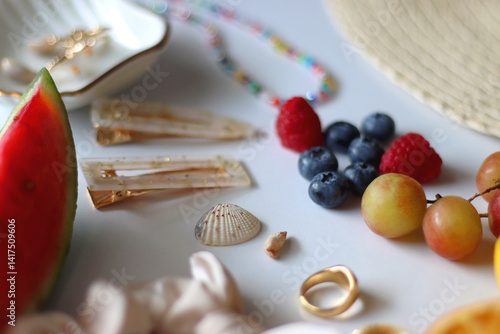 Straw hat, sunglasses, seasonal fruit, seashells and colorful accessories on white backgrounds. Cute summer essentials. Selective focus.