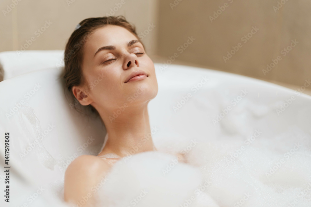 Relaxed woman enjoying a bubble bath in a modern bathroom, closed eyes and serene expression. Wellness and self-care concept with soft lighting.