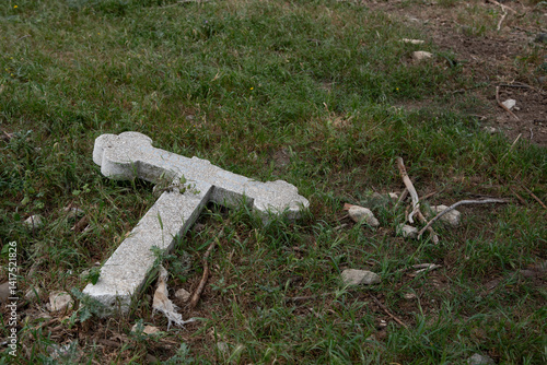Obraz na płótnie Fallen cross lying on grass symbolizing loss and grief. Ruined orthodox cemetery w salonie