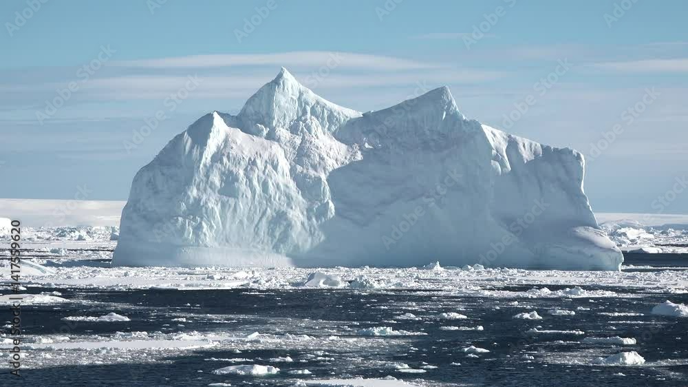 Large iceberg floats in clear waters under a bright blue sky, showcasing the beauty of Arctic nature and climate impact Large iceberg floats in clear waters under a bright blue sky, showcasing the beauty of Arctic nature and climate impact