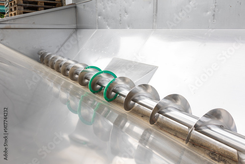 Industrial auger conveyor system transporting materials in modern factory