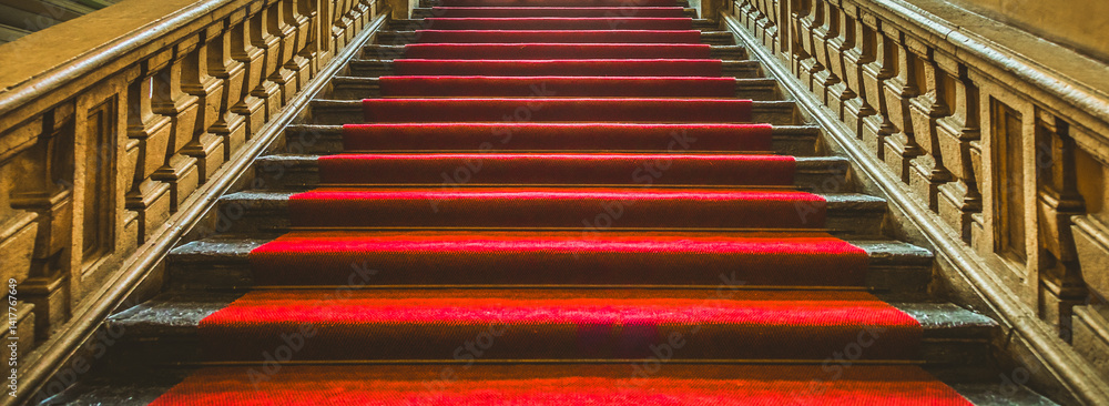 Vintage dark staircase with red carpet.