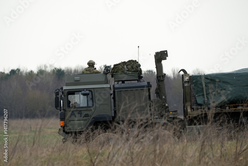 Obraz na płótnie Soldier lookout in the cab of British army MAN SV HX 8x8 eight wheeled logistics truck carrying supplies across countryside w salonie