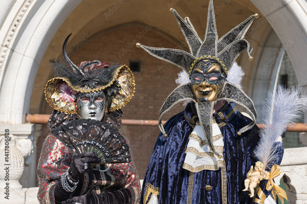 Obraz premium Venice, Italy - People dressed in carnival masks are photographed by tourists in the scenery of the ancient Venetian palaces