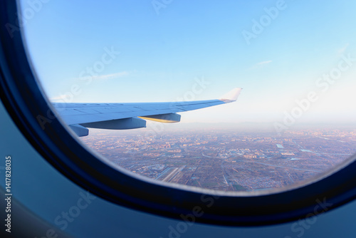 Sunset view from airplane window, airplane wing and earth as seen through window at cloudy sky.