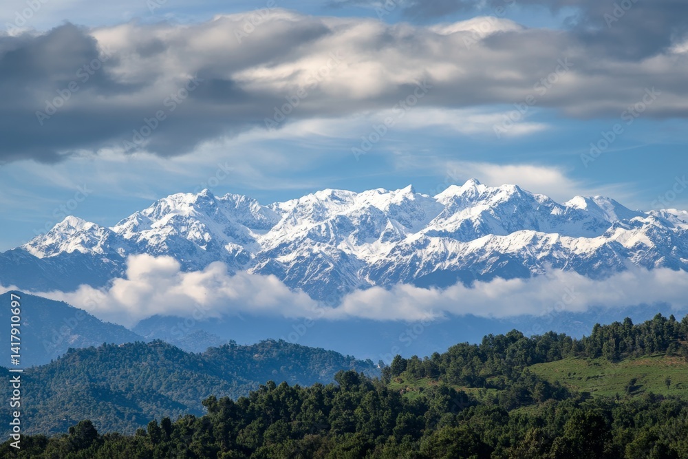 Naklejka premium Snowy mountain range, lush valley, dramatic clouds